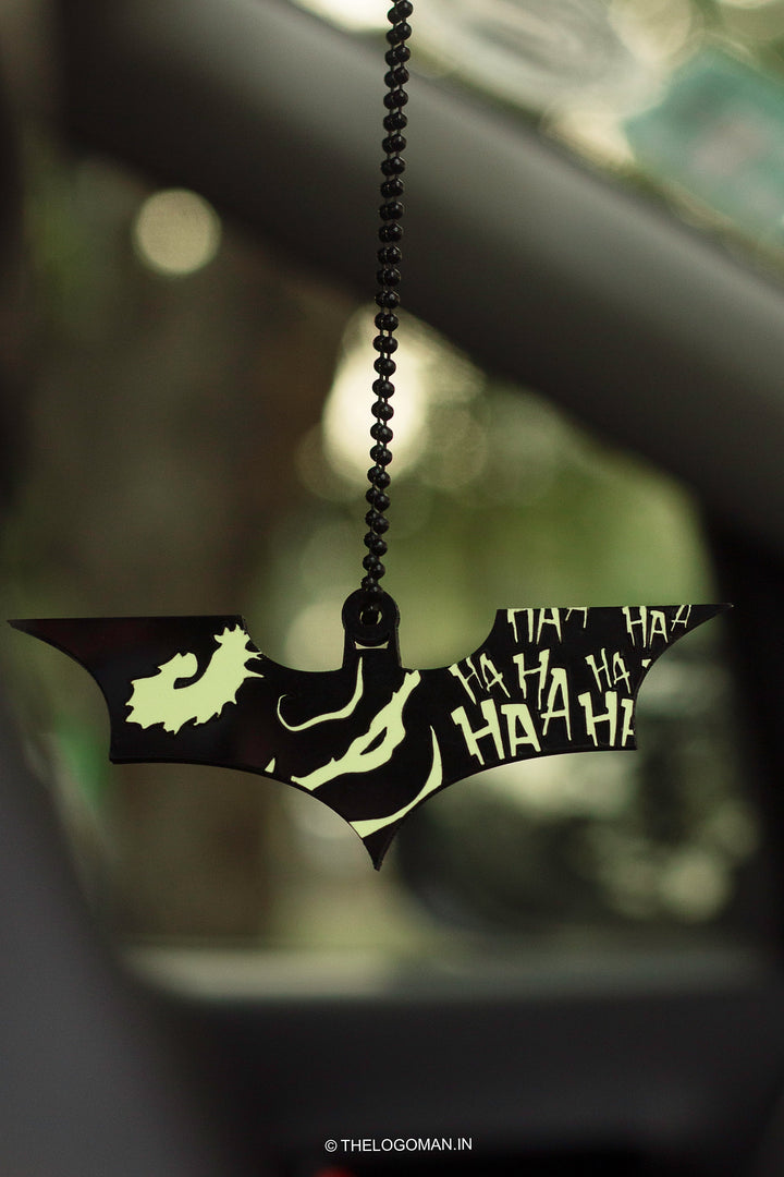 Glowing bat-shaped car accessory with 'HA HA HA' text hanging from a car's rearview mirror.