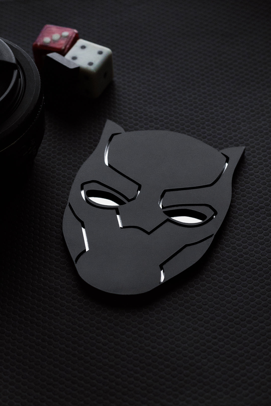 Black panther mask on a textured black surface with dice and poker chips in the background.