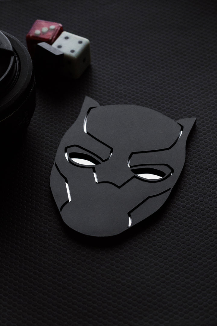 Black panther mask on a textured black surface with dice and poker chips in the background.