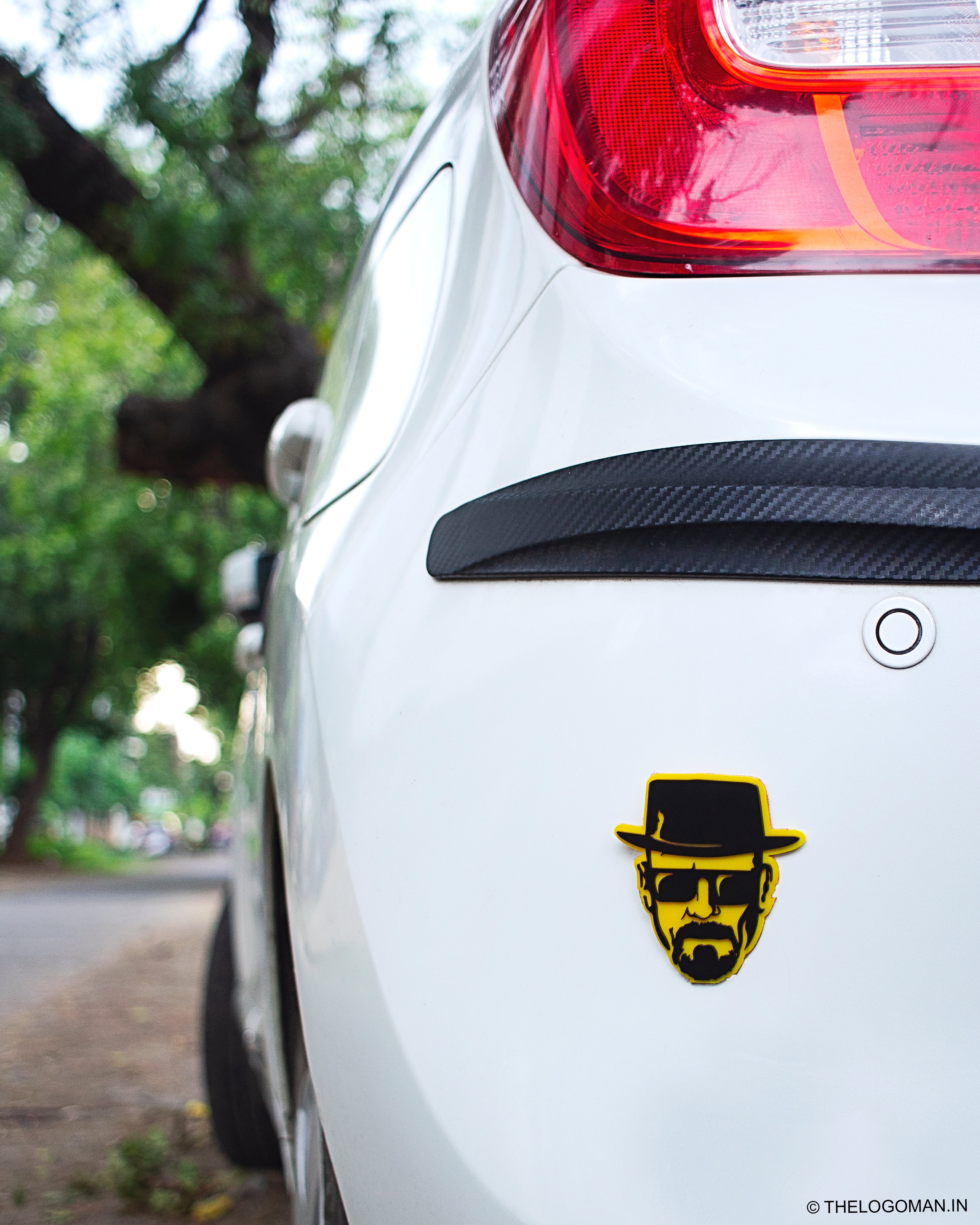 Car with a yellow and black logo on the back, outdoors.