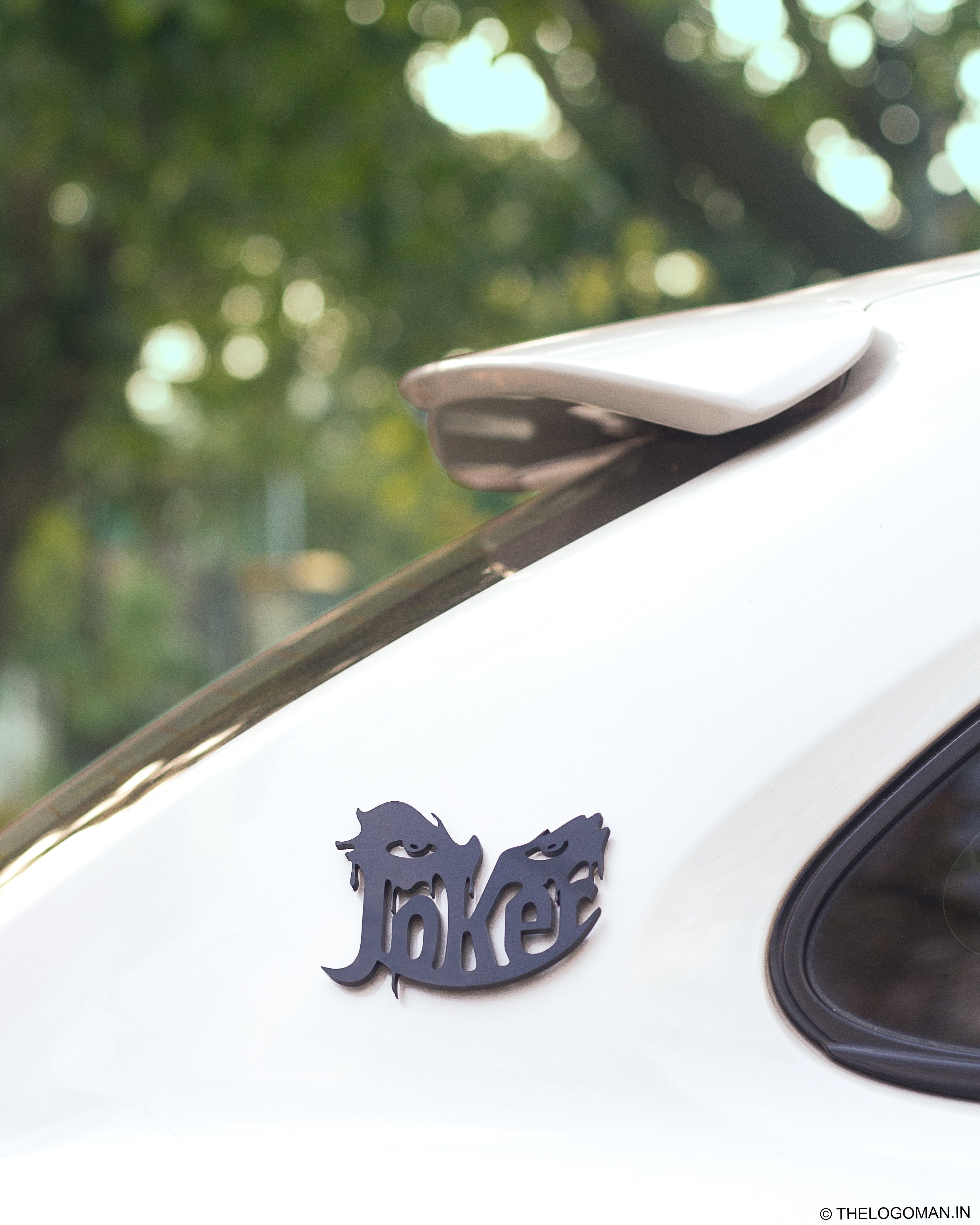 Car with a decorative emblem on the hood against a blurred green background