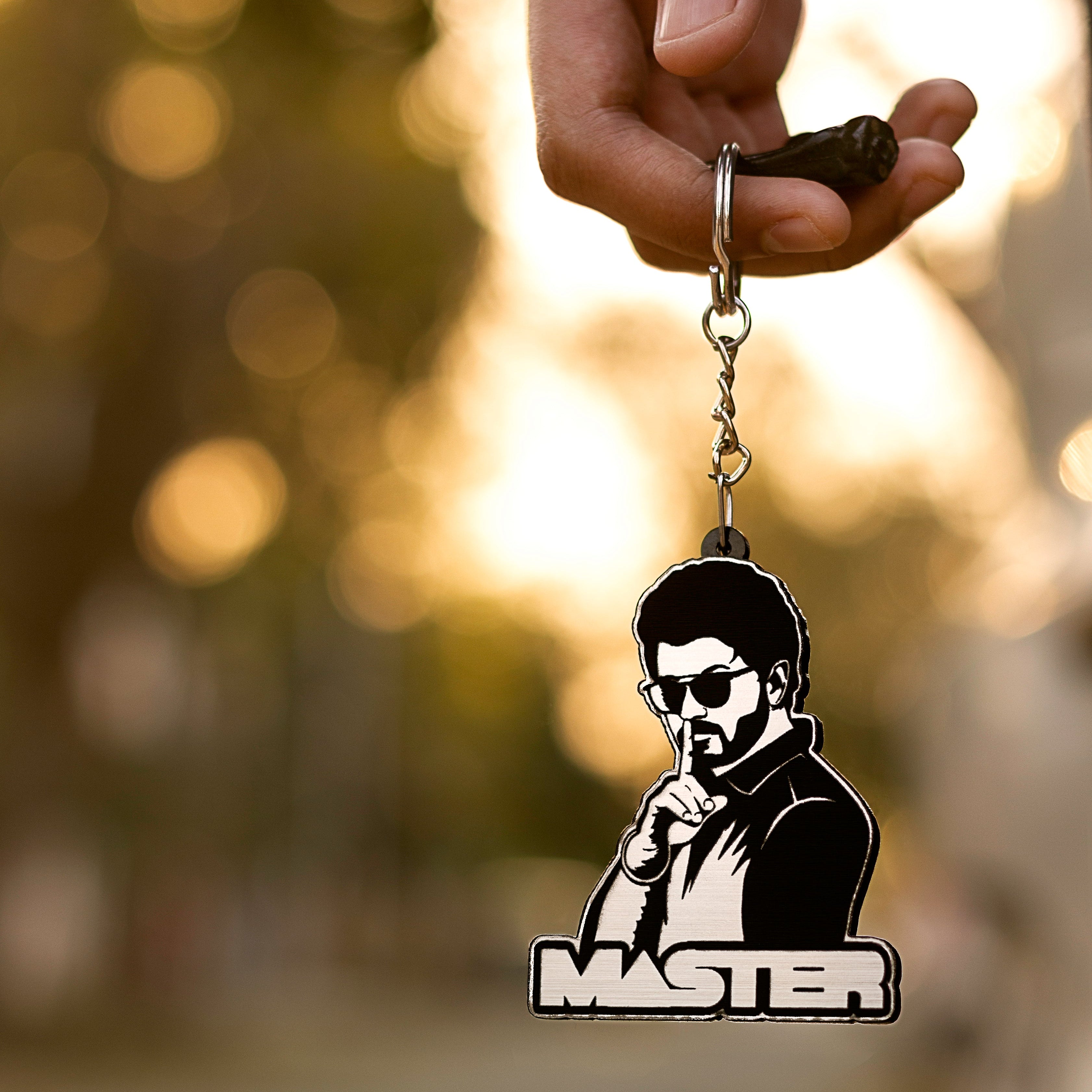 Keychain with a silhouette of a person and 'Master' text, held in a hand against a blurred natural background.