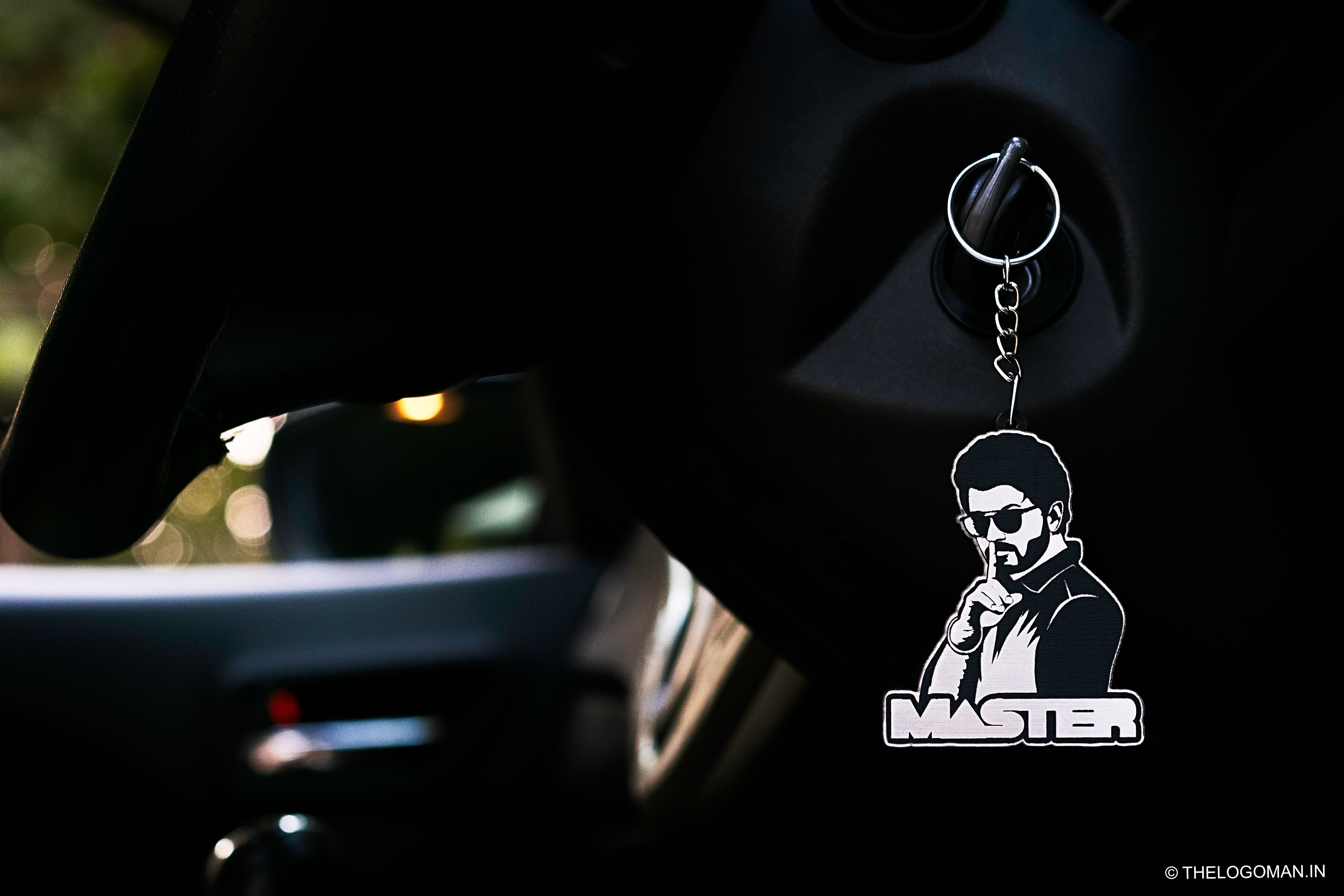 Keychain with a stylized illustration of a person and the word 'Master' attached to a car's rearview mirror.