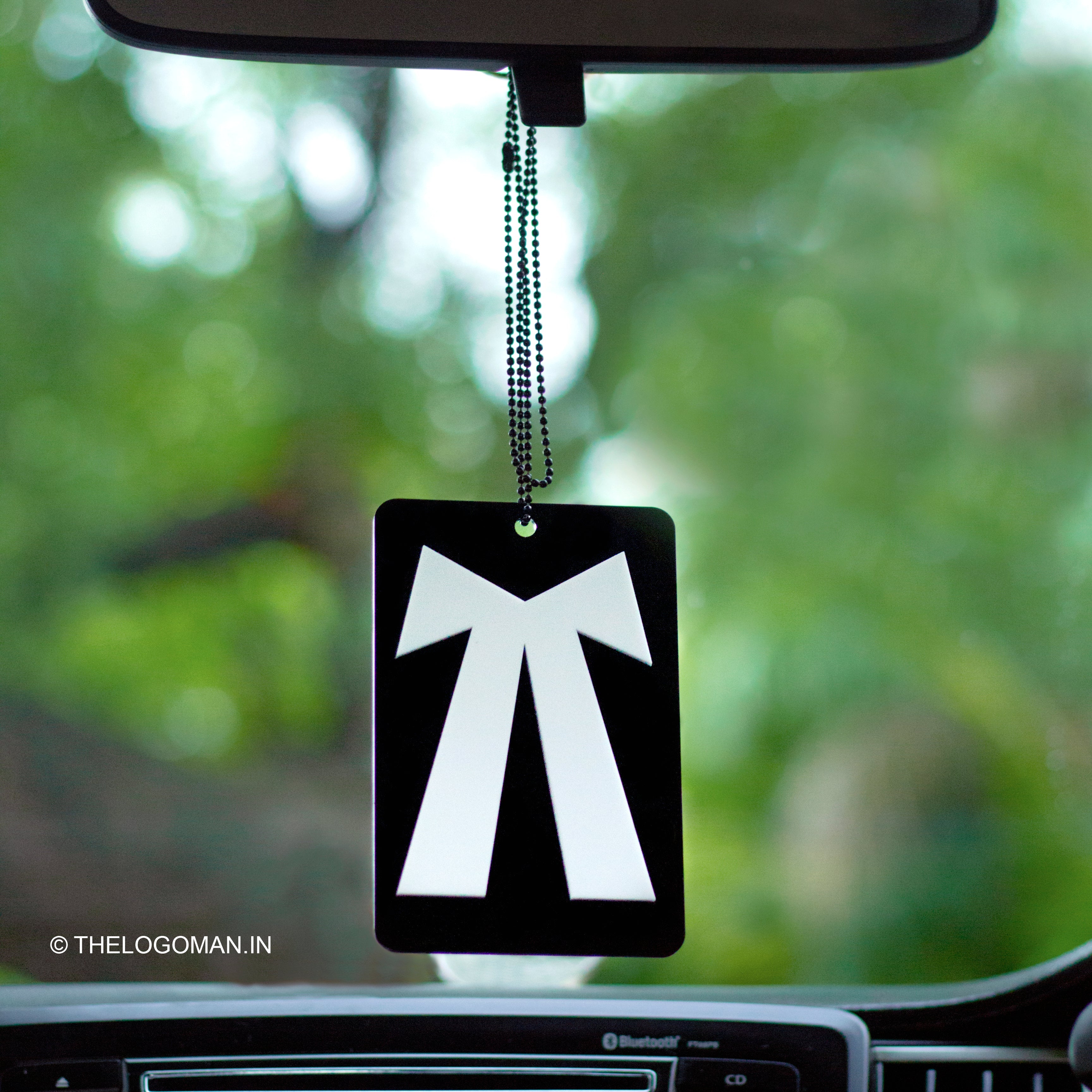 Car air freshener with a black and white design hanging from a car's rearview mirror.