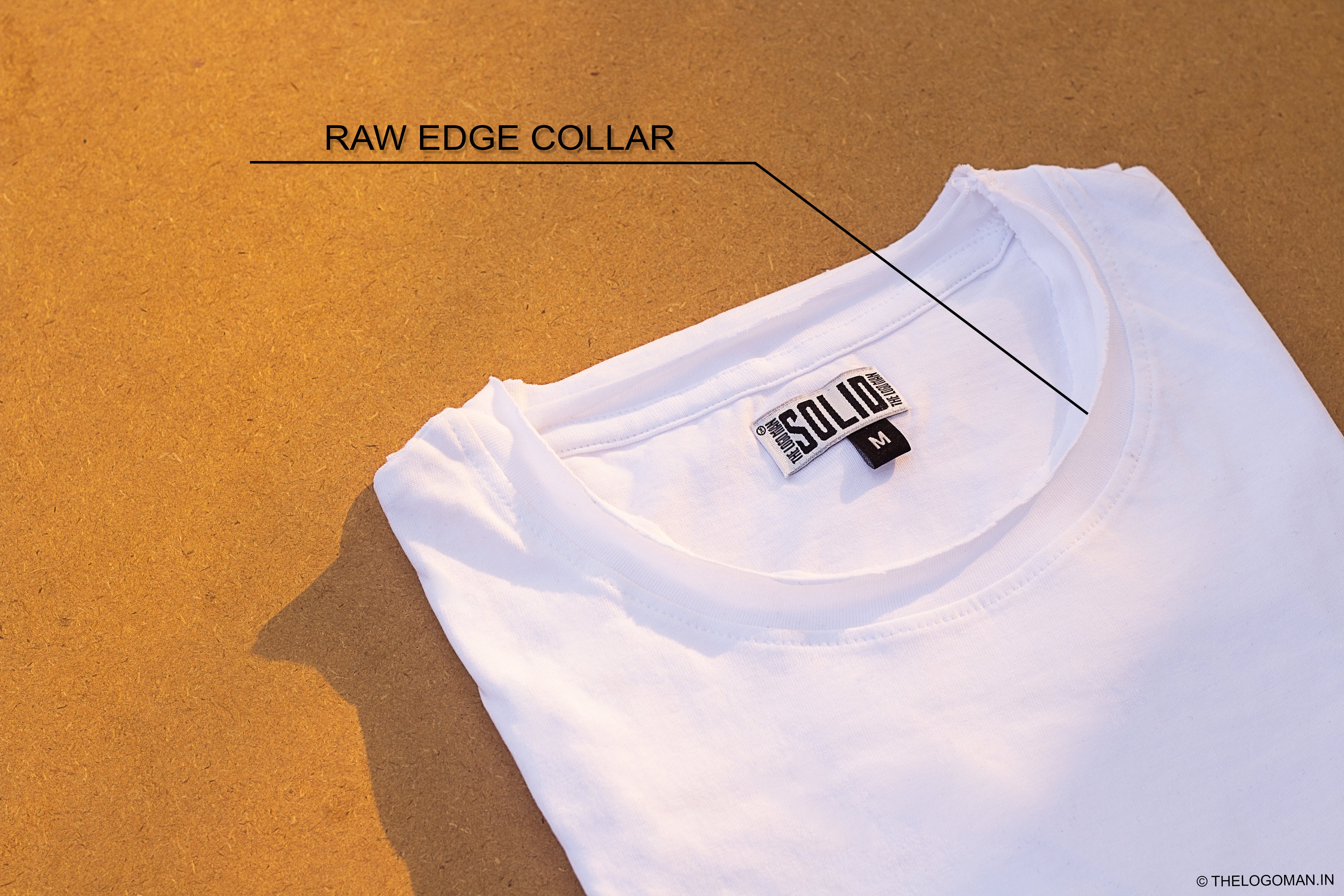 White t-shirt with a raw edge collar on a brown background